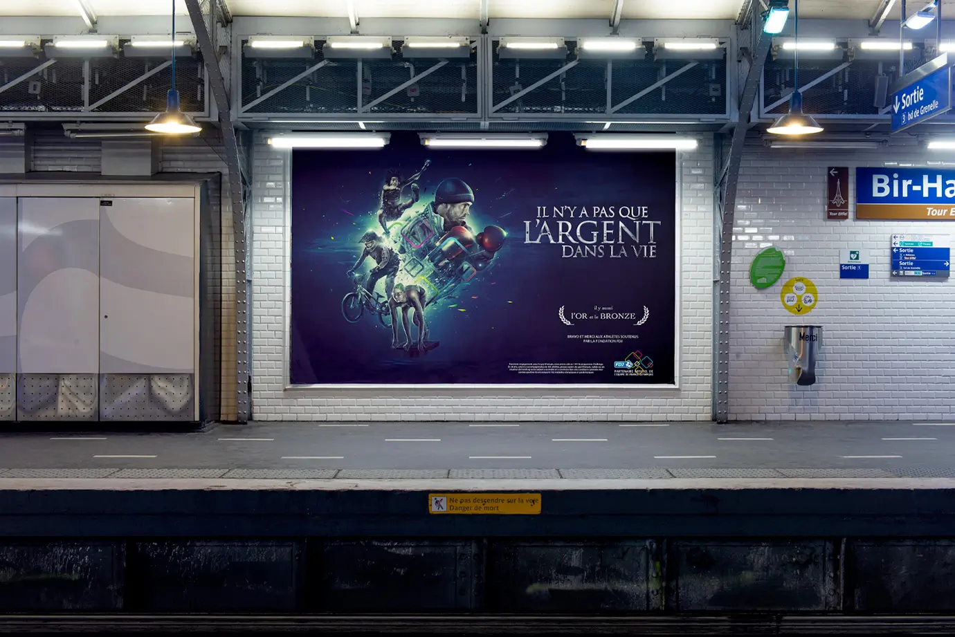 Affiche publicitaire de la FDJ, mettant en scène 4 sportifs olympiques dans un univers créatif coloré et dynamique avec le texte 'Il n'y a pas que l'argent dans la vie, il y a aussi l'or et le bronze' pour une campagne de promotion des valeurs humaines et sportives. L'affiche est située dans une station de métro à Paris.