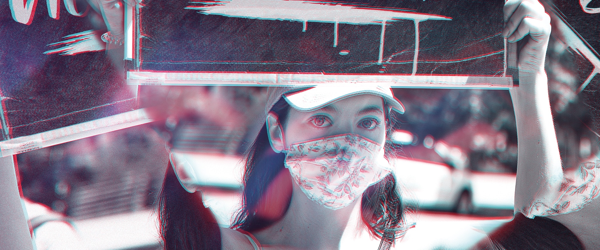 Photographie d'une jeune femme portant une visière et un masque facial à motifs floraux, tenant un panneau lors d'une manifestation ou d'un événement public. La photographie est prise à travers un prisme donnant une dimension supplémentaire à l'image, renforçant l'impact visuel de la scène capturée.