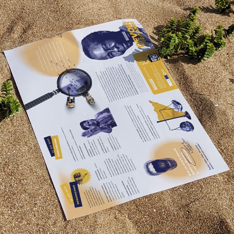 Une brochure sur le devoir de vigilance dépliée repose sur le sable. Elle présente un mélange de contenu texte et d'images, dont des portraits et des graphiques en jaune et bleu. Des plantes vertes émergent du sable autour de la brochure, ajoutant une touche de nature à la scène.