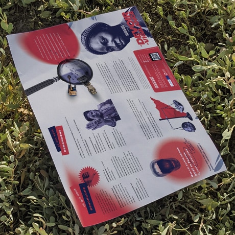 Une brochure informative avec des éléments graphiques en rouge et bleu est posée sur un buisson vert. La brochure comporte des images de personnes, des textes explicatifs, et des titres accrocheurs. Le cadre naturel et la brochure créent une juxtaposition entre les ressources éducatives et l'environnement extérieur.