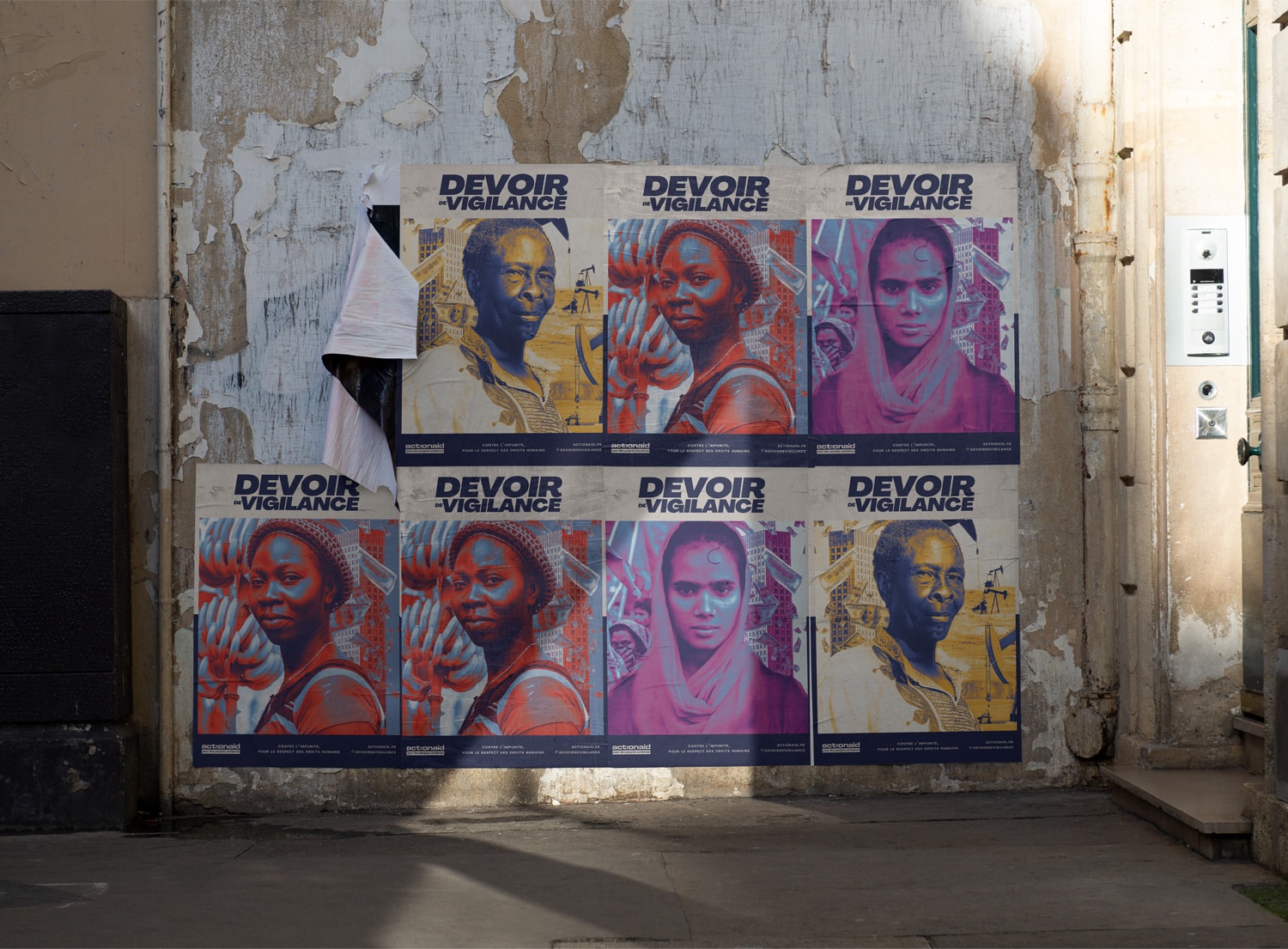 Un mur usé sert de fond à une série d'affiches avec le slogan 'DEVOIR DE VIGILANCE'. Chaque affiche présente des portraits colorés et captivants de différentes femmes, activistes ou défenseuses des droits humains. Les affiches en bleu, jaune et violet sont disposées en mosaïque et certaines sont superposées, avec une affiche partiellement décollée qui ajoute à l'effet urbain et à la texture de l'ensemble.